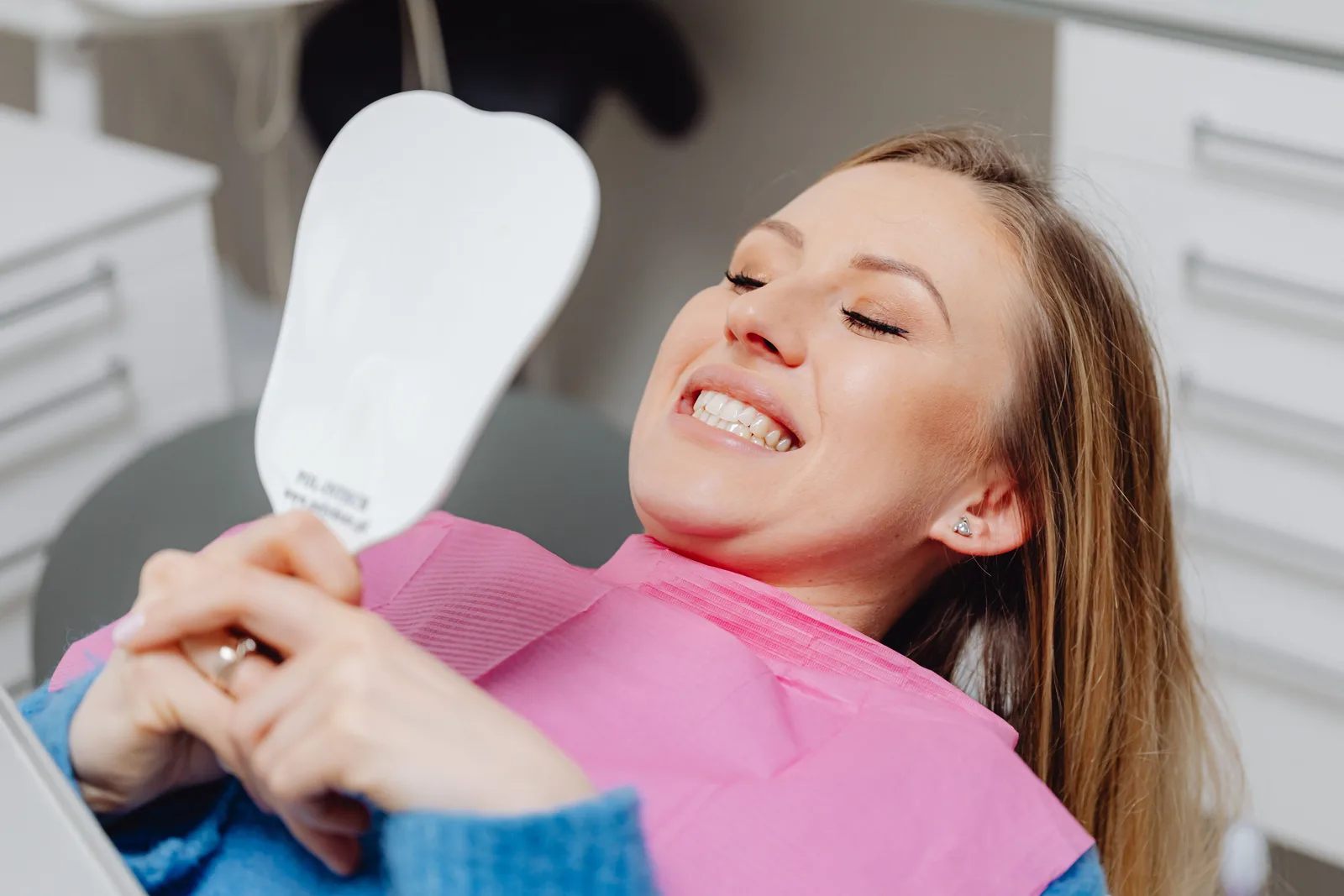 Patient checking her smile in the mirror, shown while covering All-on-6 Implants in Virginia Beach