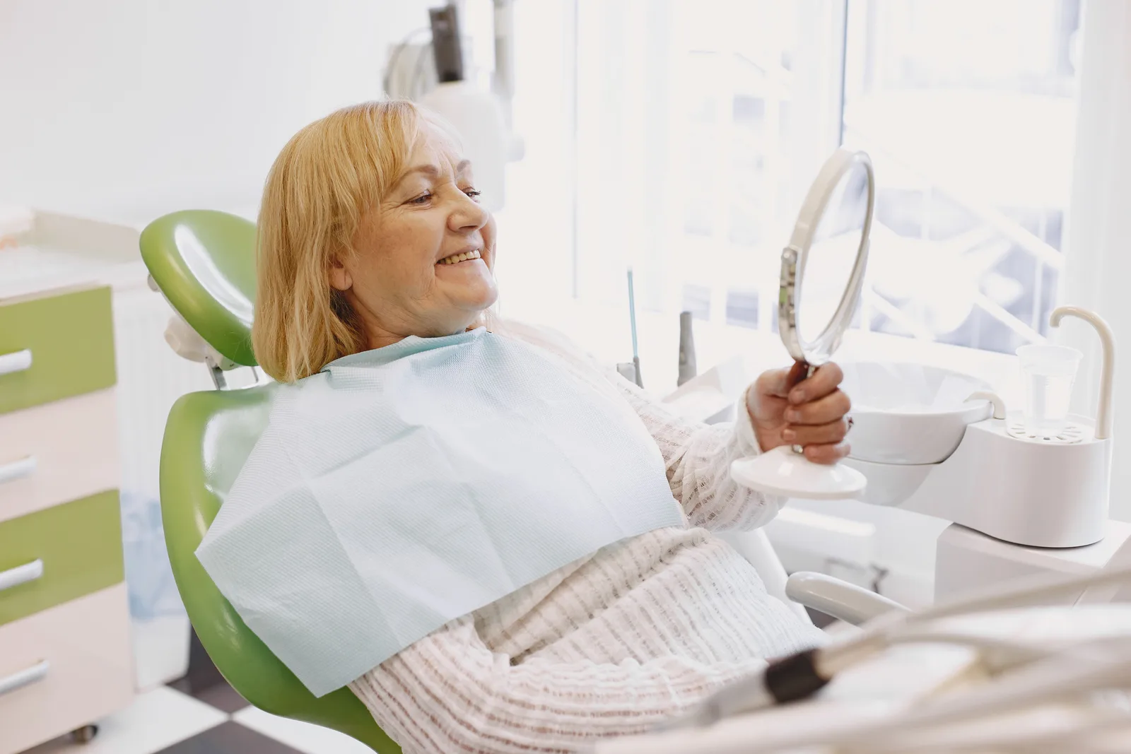 Patient reviewing a new smile in the mirror, shown while covering Full Mouth Cost in Virginia Beach