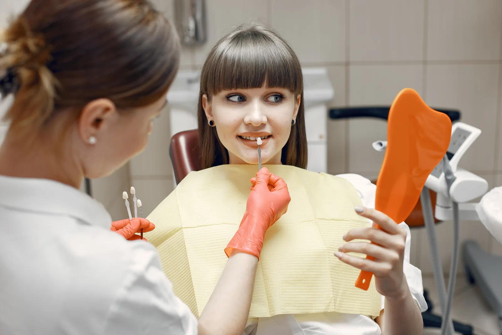 Patient checking crown shade in a hand mirror, shown while covering Single Tooth Implant in Virginia Beach