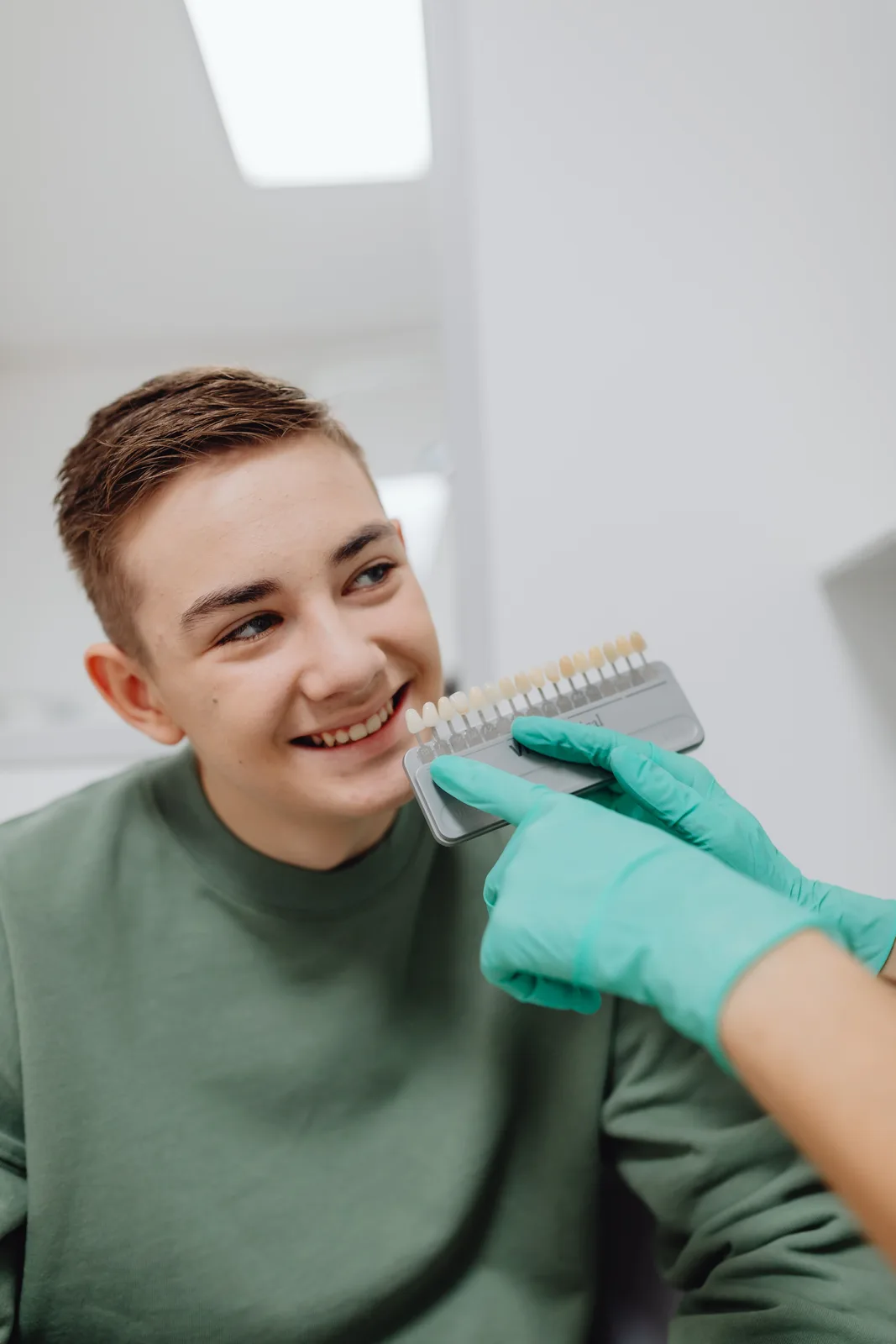 Shade guide held beside the patient smile, shown while covering Dentures Vs Implants in Virginia Beach